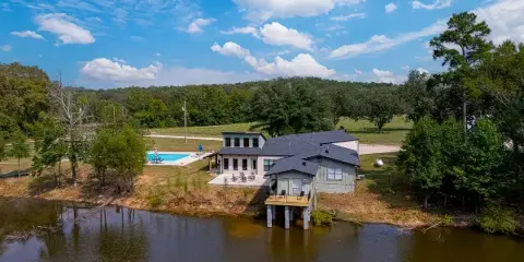 Aerial view of the Hips Hollow Farm venue featuring a large house, a swimming pool, and a pond surrounded by trees.