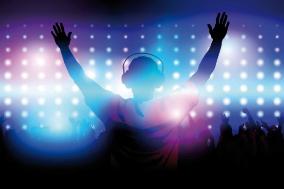 Silhouette of a DJ with raised hands and headphones in front of a crowd and colorful stage lights.