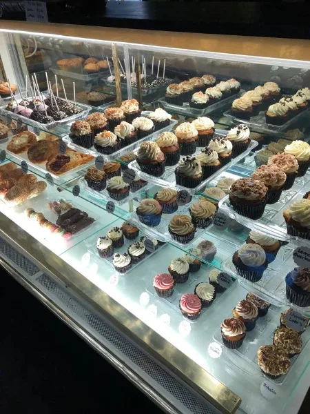 A bakery display case filled with various cupcakes and pastries.