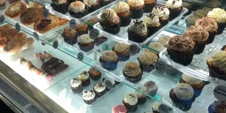 A bakery display case filled with various cupcakes and pastries.