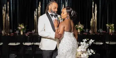 A bride and groom dancing in a ballroom beneath a large floral chandelier installation.