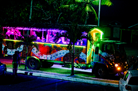 A party bus with colorful interior lighting and passengers visible through the windows at night.