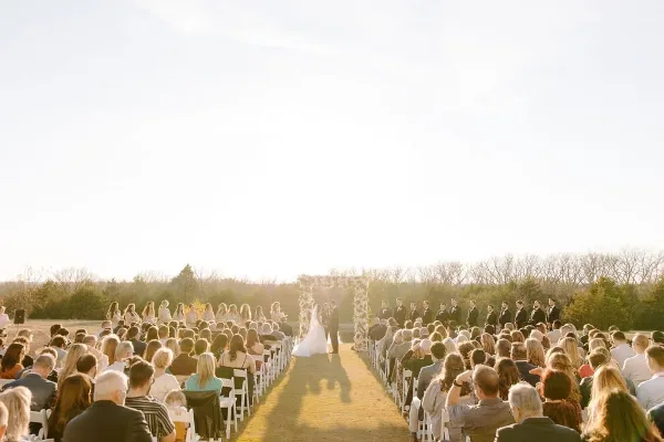 Outdoor wedding ceremony with a floral arch and aisle arrangements