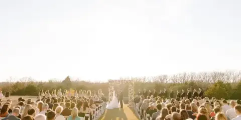 Outdoor wedding ceremony with a floral arch and aisle arrangements
