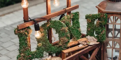A wooden cart decorated with moss-covered letters and string lights, representing event rental decor.