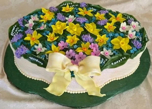 A custom designed cake decorated with colorful fondant flowers and a large fondant bow.
