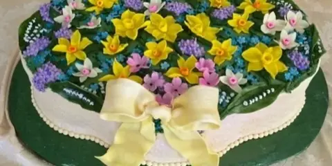 A custom designed cake decorated with colorful fondant flowers and a large fondant bow.