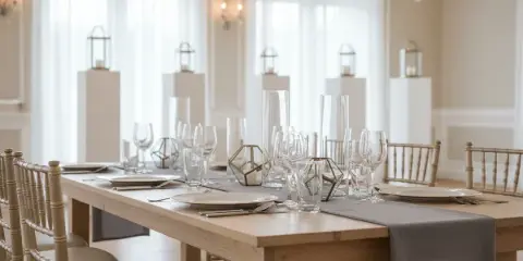A wedding reception tablescape featuring a long wooden farmhouse table, champagne Chiavari chairs, and crystal stemware.