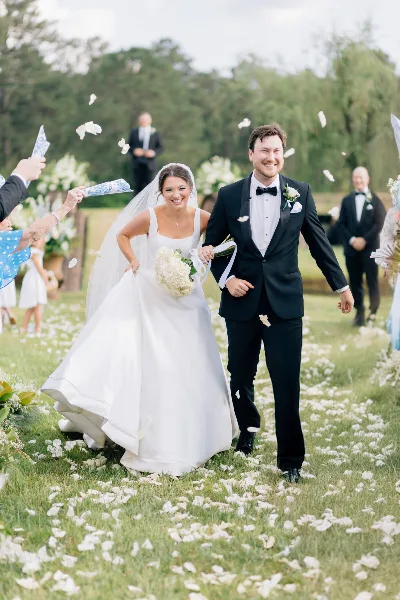 A bride and groom walking down a petal-strewn aisle during a wedding ceremony.