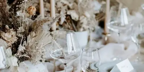 A close-up of an elegant wedding table setting featuring dried floral arrangements, tall candles, and glassware.