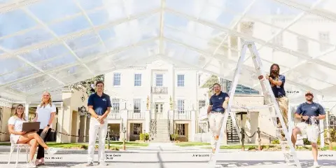 Gulf Coast Events & Rentals staff installing a clear event tent in front of a venue building