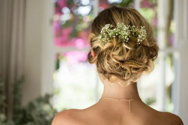 Back view of a woman with a styled bridal updo featuring baby's breath flowers.