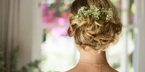 Back view of a woman with a styled bridal updo featuring baby's breath flowers.