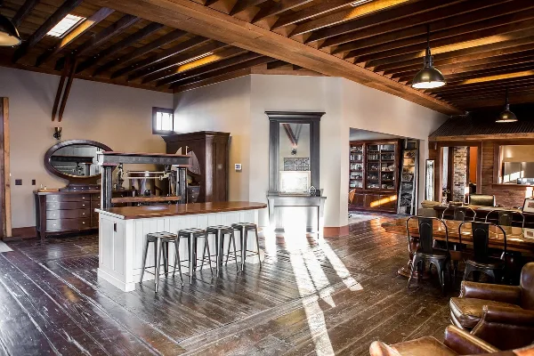 Interior of a historic wooden event venue with exposed beams, a bar, stools, and seating area
