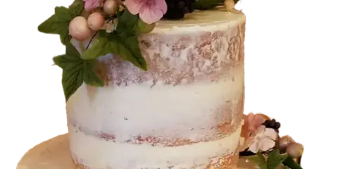 A semi-naked style cake decorated with pink sugar flowers, green leaves, and blackberries.