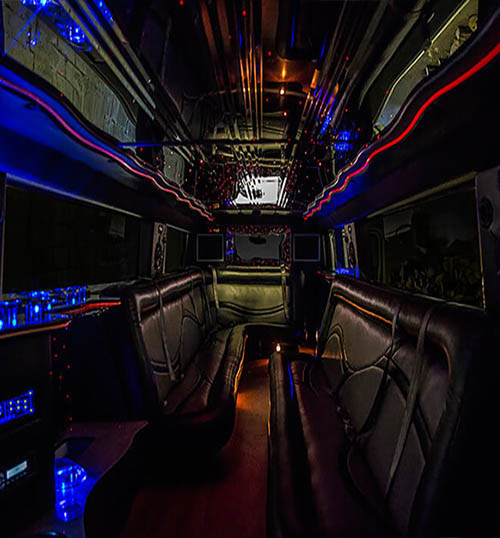 Interior view of a party bus featuring leather bench seating and colorful LED lighting.
