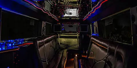 Interior view of a party bus featuring leather bench seating and colorful LED lighting.