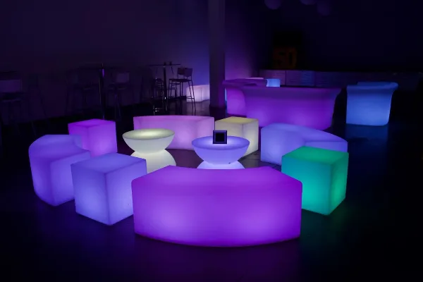 A collection of illuminated LED lounge furniture, including cubes and seating, arranged in a dark room.