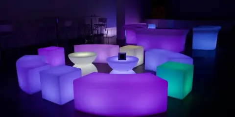 A collection of illuminated LED lounge furniture, including cubes and seating, arranged in a dark room.