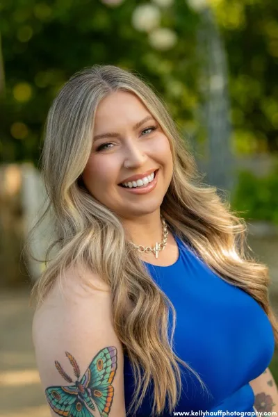 Portrait of Jess Montalvo, a professional makeup artist, smiling outdoors.