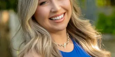 Portrait of Jess Montalvo, a professional makeup artist, smiling outdoors.