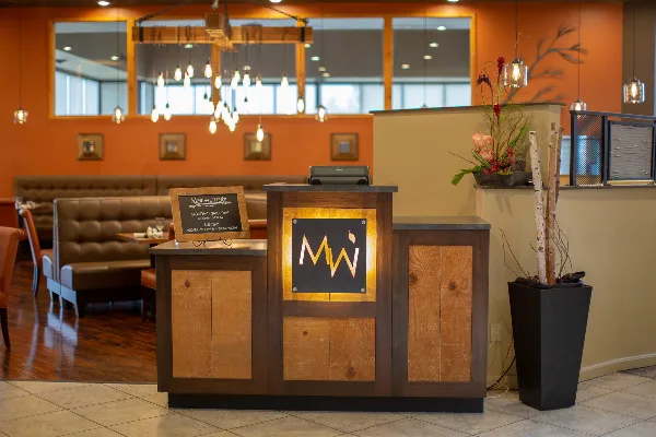 Interior view of Meriwether's Bistro showing the wooden host stand with the restaurant's name and logo, surrounded by dining booths and warm lighting.