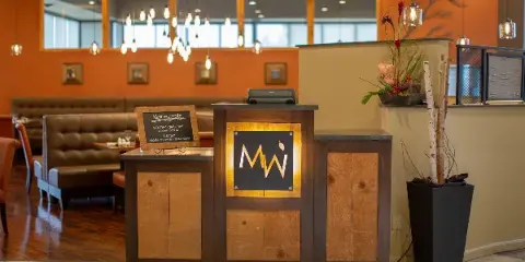 Interior view of Meriwether's Bistro showing the wooden host stand with the restaurant's name and logo, surrounded by dining booths and warm lighting.
