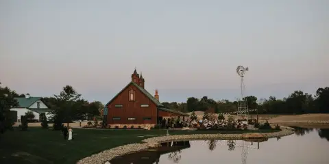 Exterior view of the Thunderhead Pines venue featuring a red barn-style building, a windmill, and a lake at dusk.