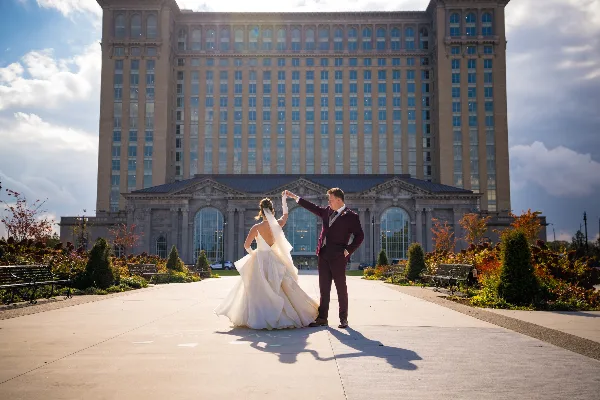 A bride and groom dancing in front of a large, historic building with a stone facade.