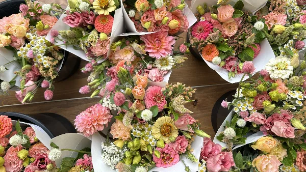An assortment of fresh, seasonal cut flower bouquets arranged in white paper wraps.