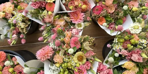 An assortment of fresh, seasonal cut flower bouquets arranged in white paper wraps.