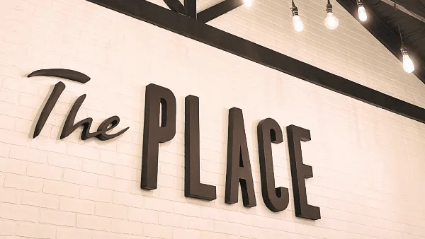 Interior wall of the venue featuring the text 'The PLACE' in dark dimensional letters against a white brick background.