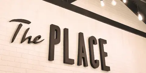 Interior wall of the venue featuring the text 'The PLACE' in dark dimensional letters against a white brick background.