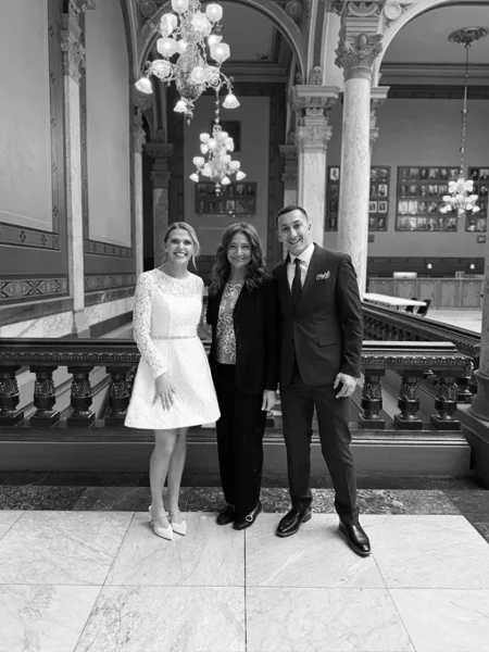 Wedding coordinator Bretta Thompson standing with a bride and groom in a formal venue.