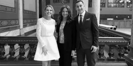 Wedding coordinator Bretta Thompson standing with a bride and groom in a formal venue.