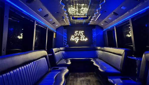 Interior view of a party bus with blue LED lighting, black leather bench seating, and a neon sign reading '515 Party Bus'.