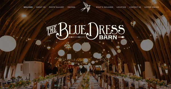 Interior view of a wedding barn venue with a high wooden ceiling, string lights, and long tables set for a reception.