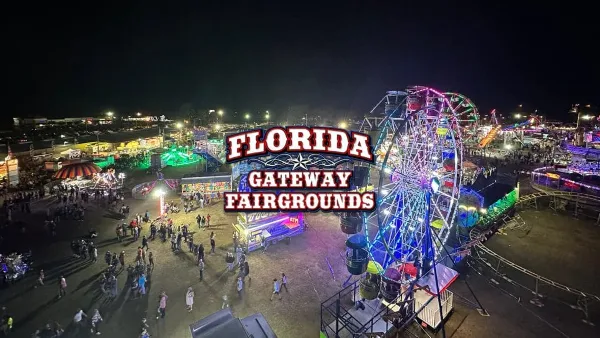 Aerial night view of the Florida Gateway Fairgrounds featuring a lit Ferris wheel, carnival rides, and crowds of people.