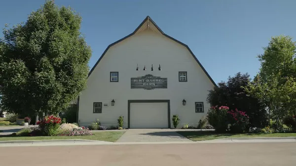 Exterior view of the white gambrel-roofed Mint Barrel Barn with a sign on the facade.