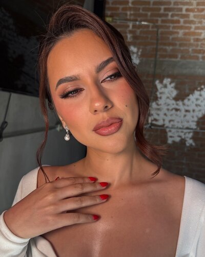 Close-up portrait of a woman with professional bridal makeup and styled hair.
