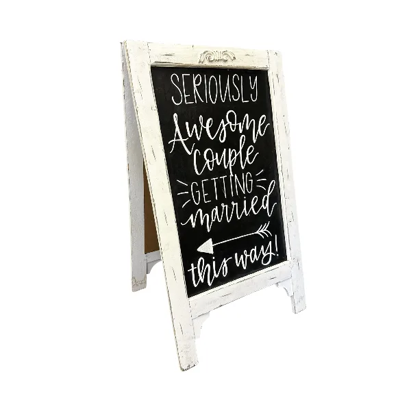 A white distressed wooden A-frame chalkboard sign with handwritten text reading 'Seriously Awesome Couple Getting Married this way!'