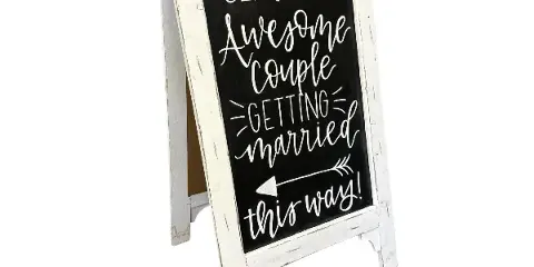 A white distressed wooden A-frame chalkboard sign with handwritten text reading 'Seriously Awesome Couple Getting Married this way!'