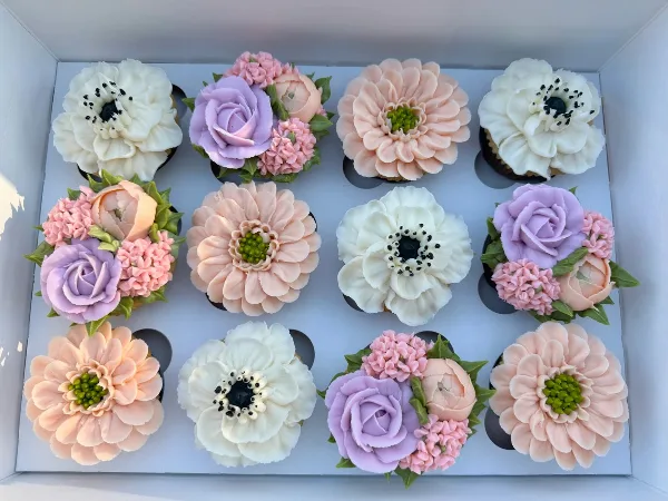 Box of pastel floral cupcakes with piped buttercream flowers