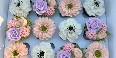 Box of pastel floral cupcakes with piped buttercream flowers