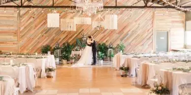 Bride and groom sharing a kiss in a rustic wedding venue.