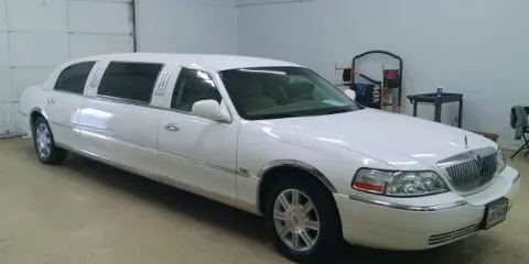 A white stretch limousine parked inside a garage.