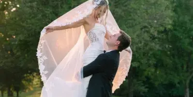 A bride and groom dancing on a green lawn with the bride's veil flowing in the air.
