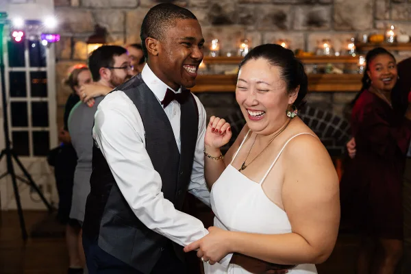A bride and groom laughing and dancing together at a wedding reception.