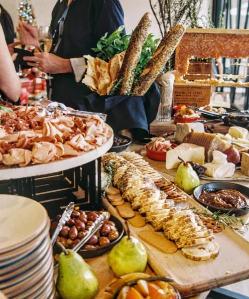 A catering table featuring a charcuterie board, baguettes, and assorted cheeses.