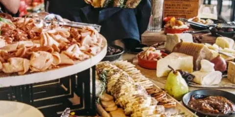A catering table featuring a charcuterie board, baguettes, and assorted cheeses.